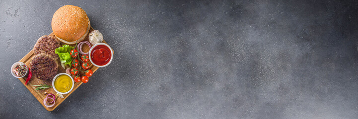 Tasty grilled homemade cheeseburgers with beef, tomato, cheese, tomato and lettuce. On dark grey background, with sauces. Top view copy space © ricka_kinamoto