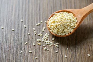 White sesame seeds in a wooden spoon on wood table top view.
