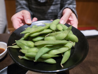 hands holding beans on a plate