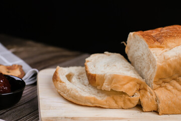 Close up fresh homemade loafs bread and sliced bread on cutting board with jam strawberry on wooden background.Healthy Diet.Prepared from a dough of flour and water, usually by baking.