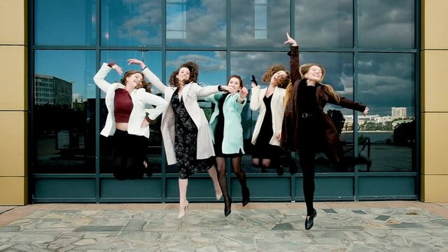 vacation and tourism concept - beautiful girls bouncing up. five girls at glass showcases. youth, youth. walk in the city. 20-25 years
