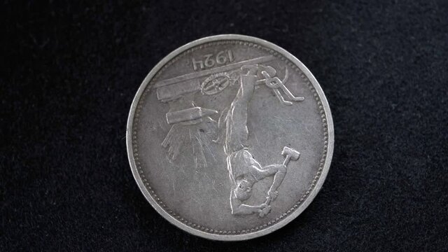 The obverse of a silver Soviet coin of fifty kopecks in denomination of 1924 is slowly rotating in front of the camera on a black background