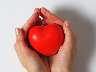 Fototapeta premium czerwone serce w rękach kobiet na białym tle na białym tle. Koncepcja dobroczynności, zdrowia i miłości