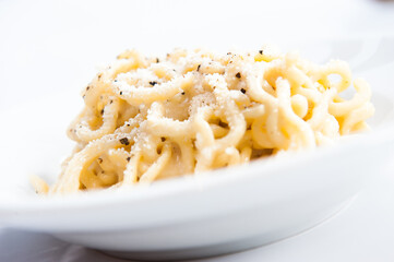 Tonnarelli cacio e pepe is a typical Lazio and Rome specialty, Italy, spaghetti with pecorino cheese and pepper  on white background
