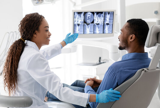 African woman dentist pointing at screen with xray picture