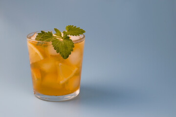 Black iced tea in a glass on blue background