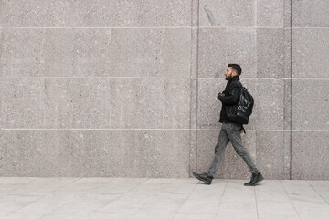 Obraz na płótnie Canvas A man in a black jacket with a backpack goes forward