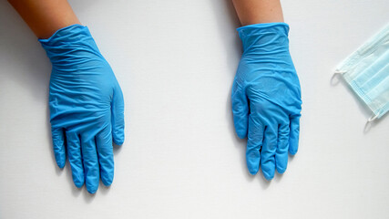           hands in blue gloves lie palms down on the table                                                     © Marina