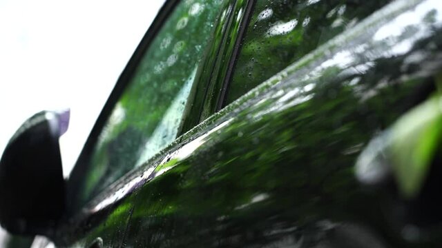 Drops of rain flow down the car..
Camera movement with a refocus on the car. On the door handle of the car lies a sheet, raindrops flow down the car. The weather is cloudy, heavy rain is pouring.
