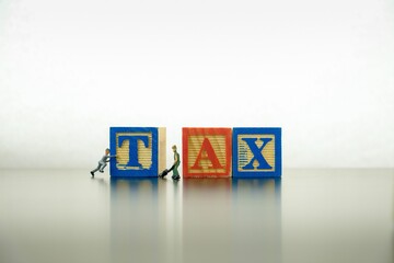 Conceptual image of working on annual tax return. Wooden block letter TAX on dark reflective...