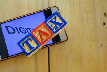 Conceptual of digital tax as government revenue. Wooden cubes on smartphone screen.