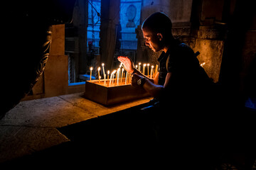 The pilgrims lit candles at the Church of the Holy Sepulchre in Jerusalem - obrazy, fototapety, plakaty