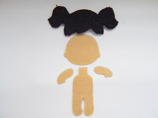 pieces of a figure of a felt doll lying next to a white background
