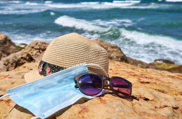 Women's accessories with a fedora straw hat and sunglasses and a face mask protection from...