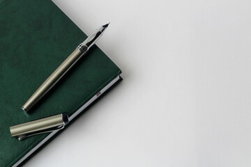 green notebook with pen on a white background