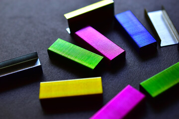 Multi-colored stapler staples on a black background