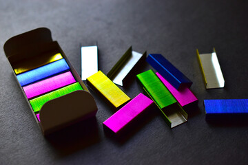 Multi-colored stapler staples on a black background