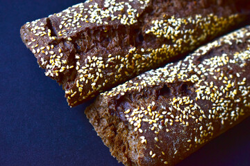 A loaf of black bread with sesame seeds on a black background
