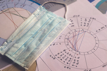 New pandemic realities of the work of a modern astrologer, the workplace of the predictor of a foggy future in the context of the COVID-19 pandemic. Astrological charts, tables, diagrams scattered in 