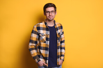 Happy  nice-looking brunette man wearing casual clothes, smiling at camera with hands in pockets,...