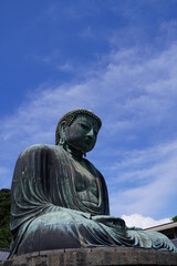 The Great Buddha of Kamakura is an outdoor bronze statue of Amida Buddha under blue sky located on the grounds of Kotoku-in Temple in Kanagawa Prefecture Japan. Kamakura Daibutsu Statue.