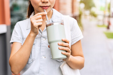 Young asian woman holding a reusable tumbler glass and walking in the city, Zero waste concept