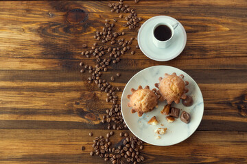 fresh chocolate muffins and cup of coffee, in a studio on a wooden background, top view