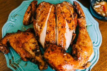Roast Chicken on a Blue Ornate Platter on a Wood Dining Table. 
