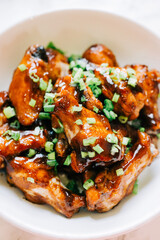 A delicious bowl of glazed barbecue Chicken Wings that are sticky and sweet and topped with spring onions. 
