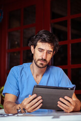 Male nurse working with his tablet outside.