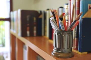 Close-up of multiple pens and pencils in a pencil holder on a desk in the library selective focus and shallow depth of field - Powered by Adobe