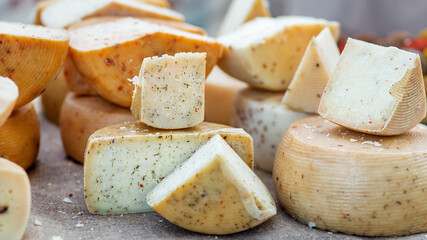 heads of hard cheese are on offer in a choice of cut pieces close-up on theme of dairy farm food.