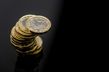 Stack of UK Sterling pound coins on a black background
