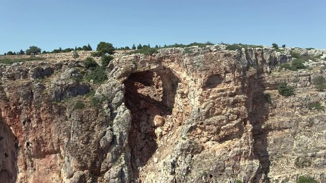 Tourists stand and look at the Keshet Cave - ancient natural limestone arch spanning the remains of a shallow cave with sweeping views near Shlomi city in Israel