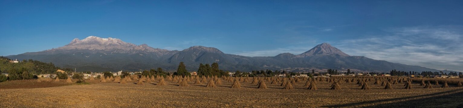 Vista panor&aacute;mica de los volcanes Popocatepetl e iztaccihuatl con sembrad&iacute;os reci&eacute;n cultivados en la parte  inferior.