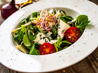 Fresh salad - blue cheese and vegetables on wooden table
