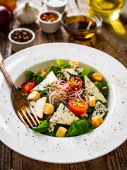 Fresh salad - blue cheese and vegetables on wooden table
