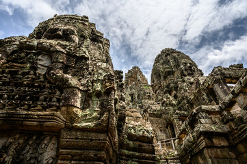 Fototapeta premium Towers with faces cravings of the ancient temple Angkor Thom next to the Angkor Wat in Siem Reap, Cambodia. Stone build old Khmer temple.