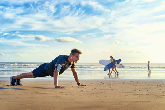 Sports and healthy lifestyle. Young man doing push-ups on the ocean beach.