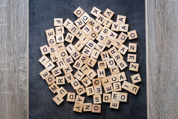 Alphabet letters on wooden pieces scattered. Random capital wooden letters