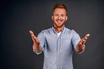 Hey long time no see. Surpirsed happy and joyful old friend with beard and moustache, pulling hands towards camera to greet mate and give warm hug, smiling broadly over grey wall