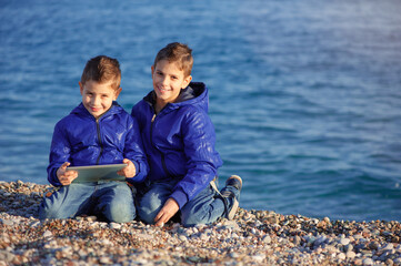 brothers with tablet pc sitting outdoors