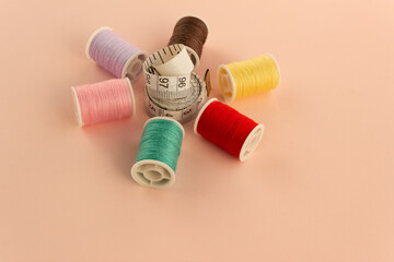 Accessories for needlework in a plain background. Spools of thread, tape measure. The layout is in...
