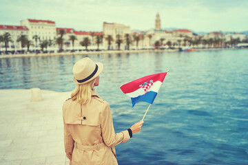 Enjoying vacation in Croatia. Young traveling woman with national croatian flag walking on Split...