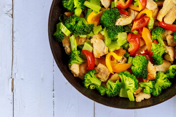 Dish with vegetable and chicken in pan on white surface.