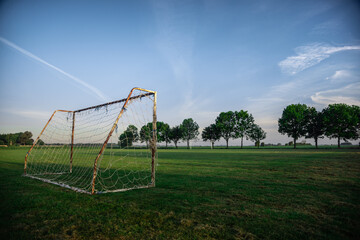 Fototapeta na wymiar soccer football goal in rural country sunrise on local town village green pitch