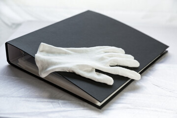 Film photography album for negative storing. White cotton archival gloves in the background. Different size negatives in special envelopes.