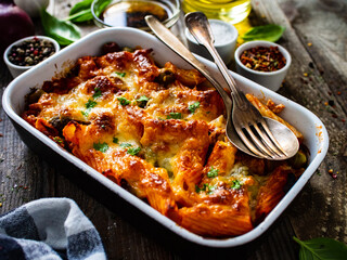 Pasta casserole with minced meat, mozzarella cheese and vegetables on wooden table
