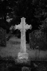 black and white gravestone cross in cemetery graveyard in evening