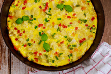 Scrambled eggs with vegetables on skillet.